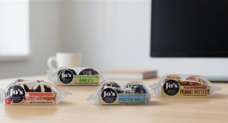 Jo's protein balls and snacks in various flavors displayed on a table.